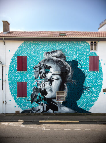 peinture murale représentant un portrait de femme recouvert d'une rose et avec de la calligraphie turquoise autour